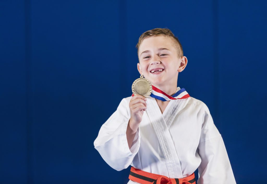 Boy shows off his medal for winning a competition.