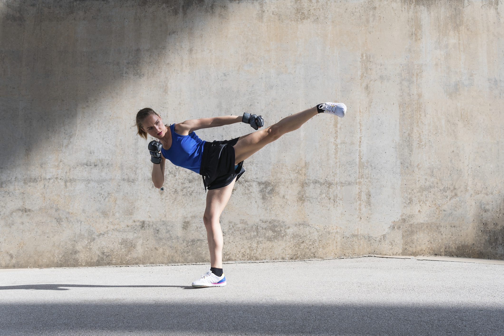 Female athlete practicing kicks in front of wall.