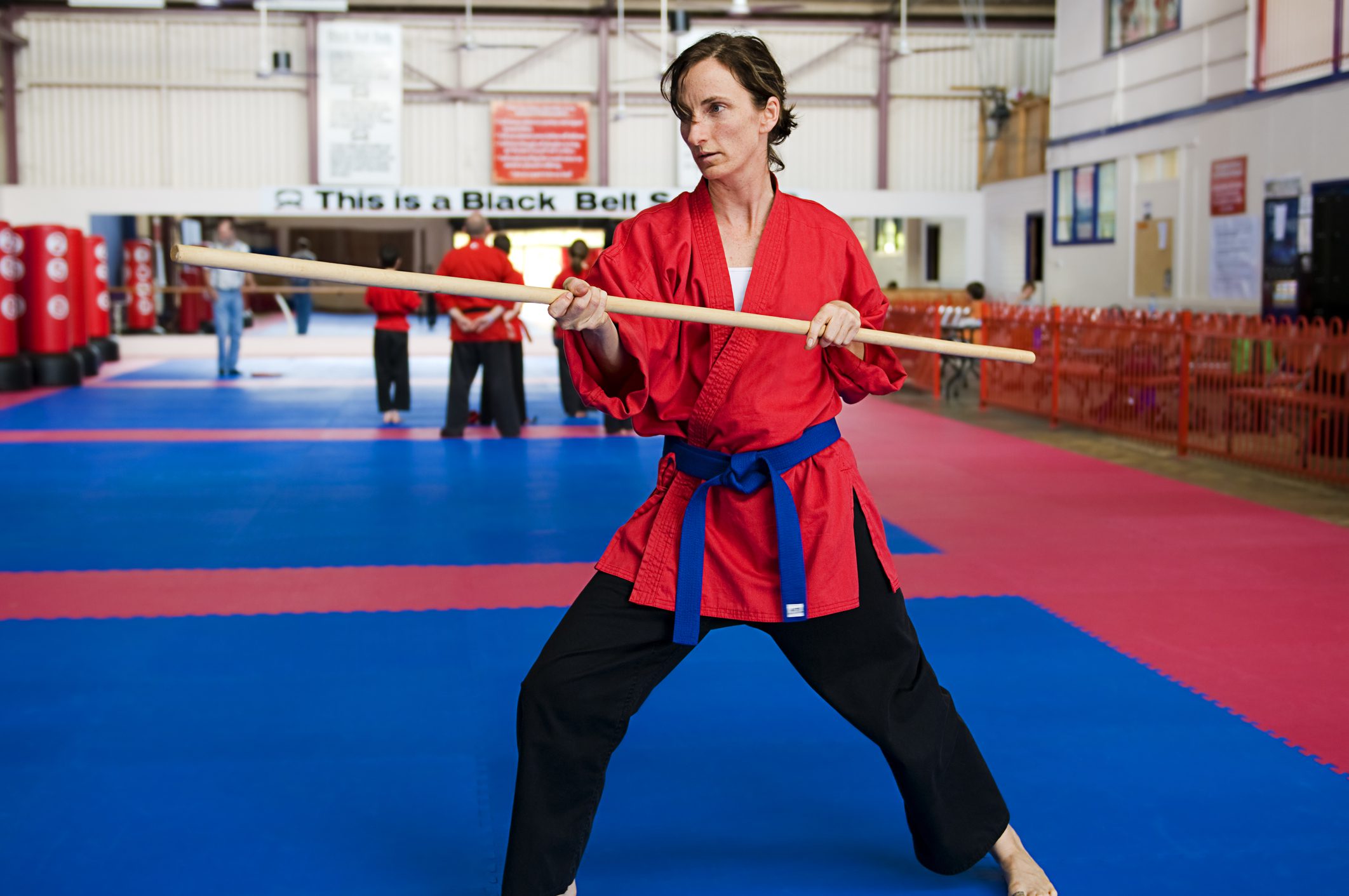 Woman practices karate stick fighting.